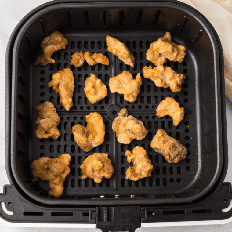 adding frozen orange chicken to air fryer while thawing sauce packet in warm water