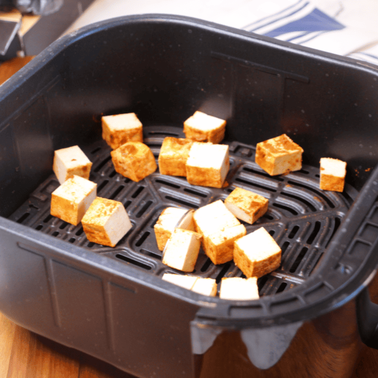 Sriracha Tofu Bites arranged in a single layer in the air fryer basket for even cooking.