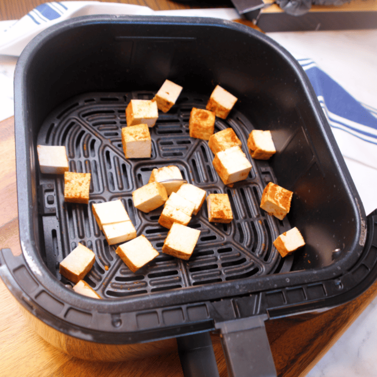 Sriracha Tofu Bites cooking in the air fryer, flipped halfway for even crispiness.