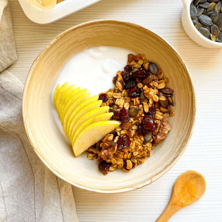 Vanilla Granola in a wooden bowl, along with yogurt, ready for serving.