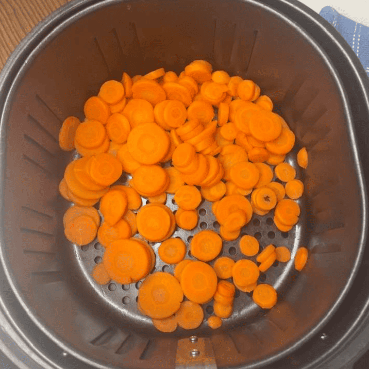 Mixing bowl with canned carrots tossed in olive oil and seasonings, evenly coated and ready for air frying.
