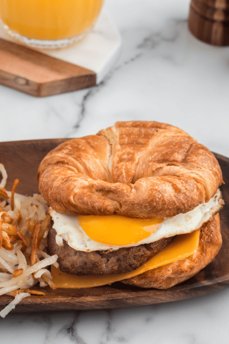 Close-up of a Burger King Sausage Egg and Cheese Croissan’wich with layers of sausage, egg, and melted cheese on a flaky croissant.