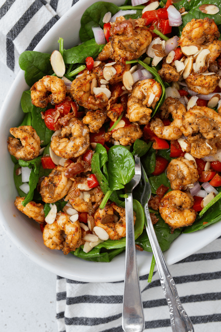 Grilled shrimp on a fresh spinach salad with crispy bacon and bacon vinaigrette drizzle.
