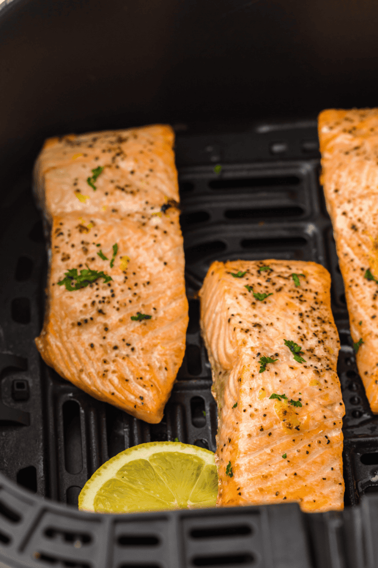 Golden honey orange glazed salmon fillet in the air fryer, garnished with fresh herbs.