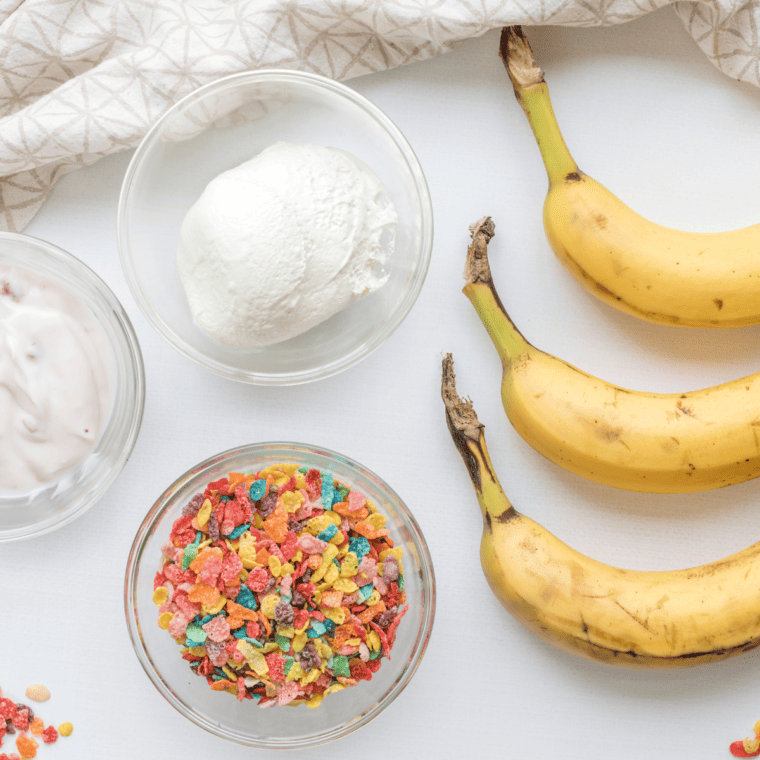 Banana halves with popsicle sticks inserted, neatly placed on a parchment-lined tray.