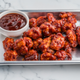 BBQ chicken bites on a plate with a bowl of homemade Heinz 57 sauce for dipping