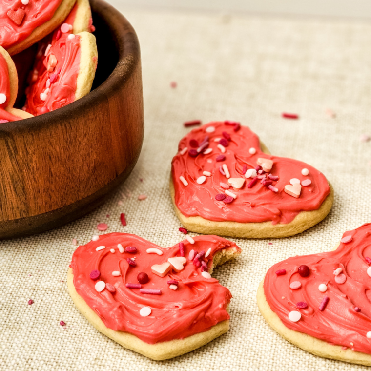 Completely cooled Valentine’s Day Lofthouse Cookies frosted with pink icing and decorated with sprinkles