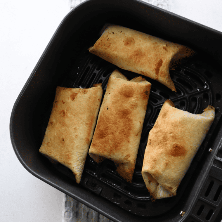 A golden, crispy Air Fryer Barn Yard Buster Wrap filled with sausage, potatoes, eggs, cheddar cheese, and creamy gravy, sliced to reveal its mouthwatering layers.