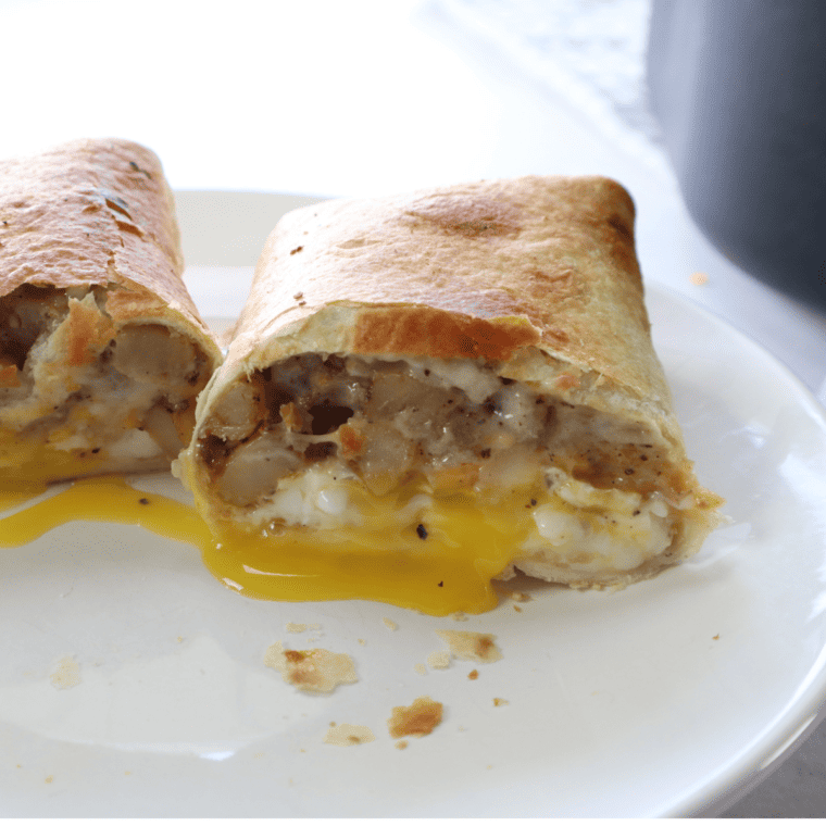 Air Fryer Barn Yard Buster Wrap filled with sausage, potatoes, scrambled eggs, cheddar cheese, and gravy, golden and crispy on the outside.
