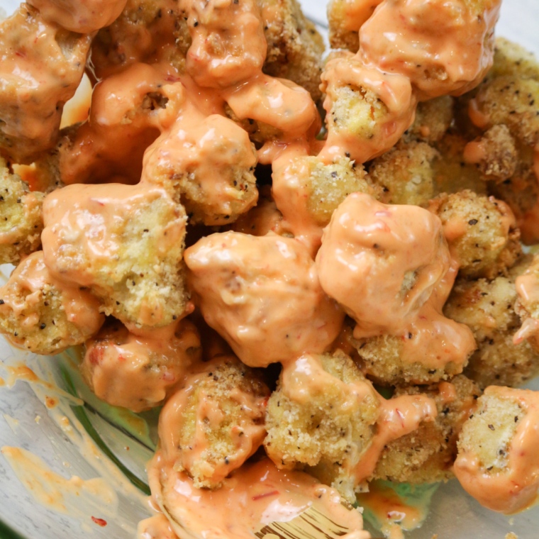 Crispy air fried cauliflower coated with creamy bang bang sauce served as a snack or side dish.