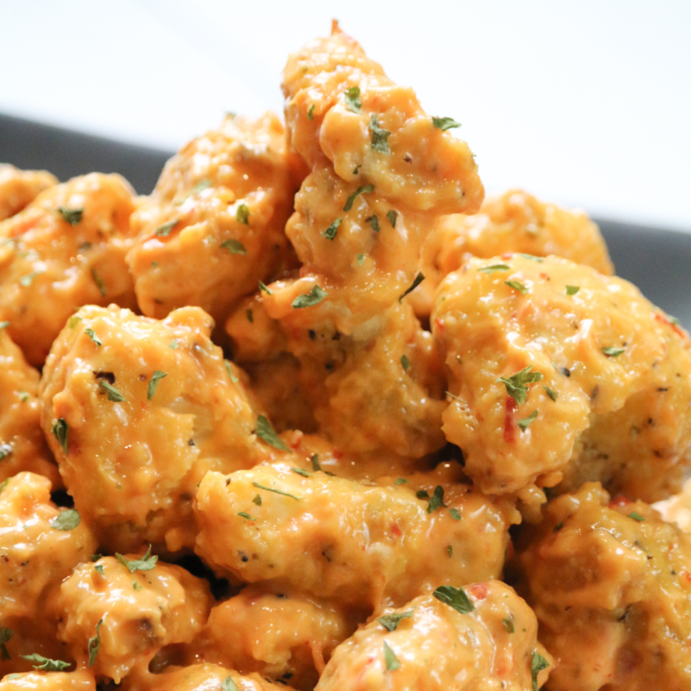 "Golden, crispy Air Fryer Bang Bang Cauliflower coated in a sweet and spicy sauce, garnished with green onions, served as a savory appetizer or side dish.