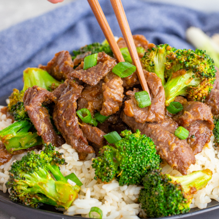 A plate of Air Fryer Beef and Broccoli with tender beef and crispy broccoli, drizzled with savory sauce and garnished with scallions.