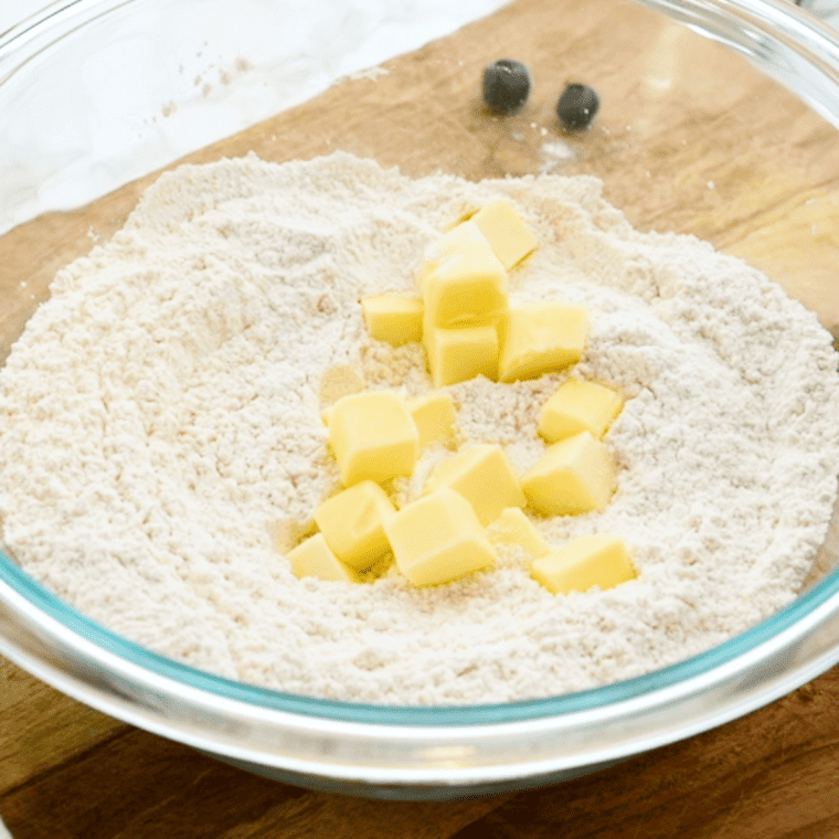 Cutting cold cubed butter into the flour mixture with a pastry cutter until it looks like coarse crumbs