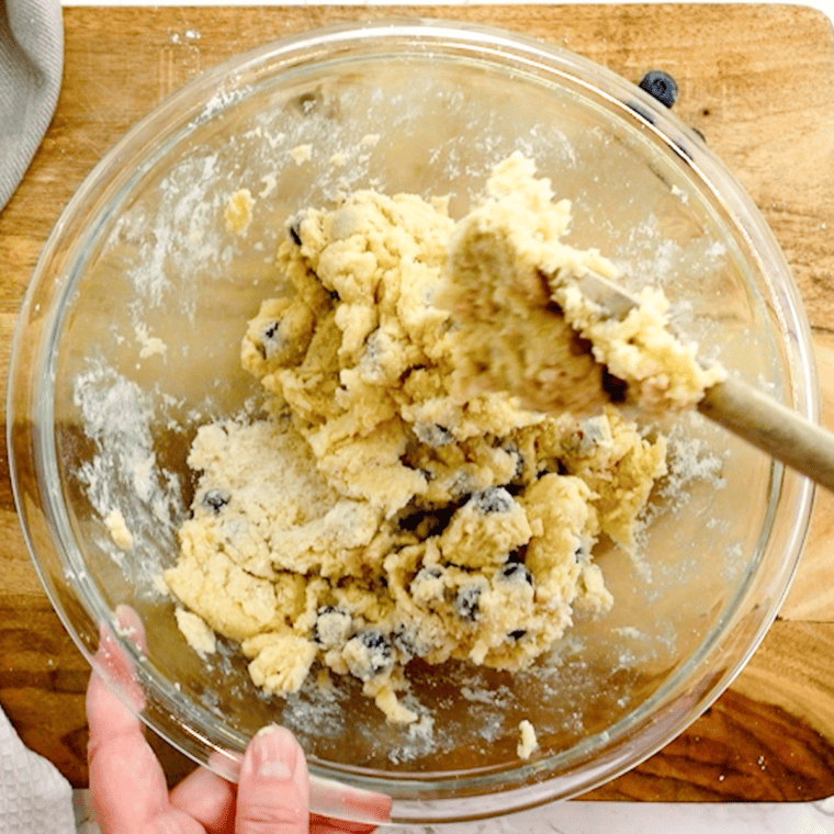 Pouring the wet ingredients into the dry mixture before gently folding in fresh blueberries