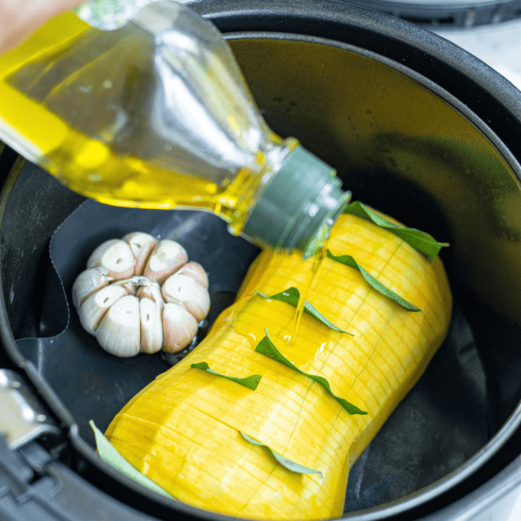 Seasoned butternut squash halves brushed with olive oil and spices, prepared for the air fryer.