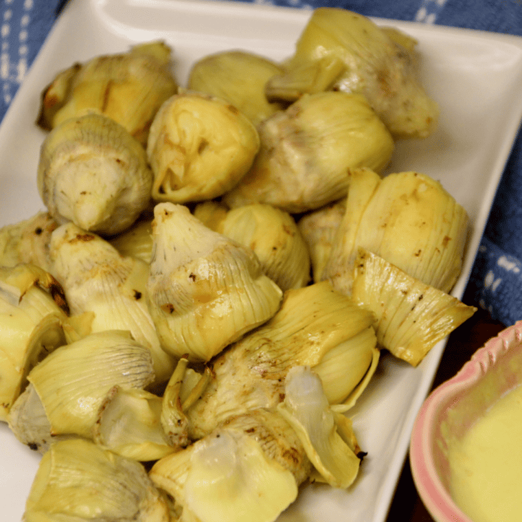 Air fried artichoke hearts in the air fryer basket, golden brown and crispy after cooking.