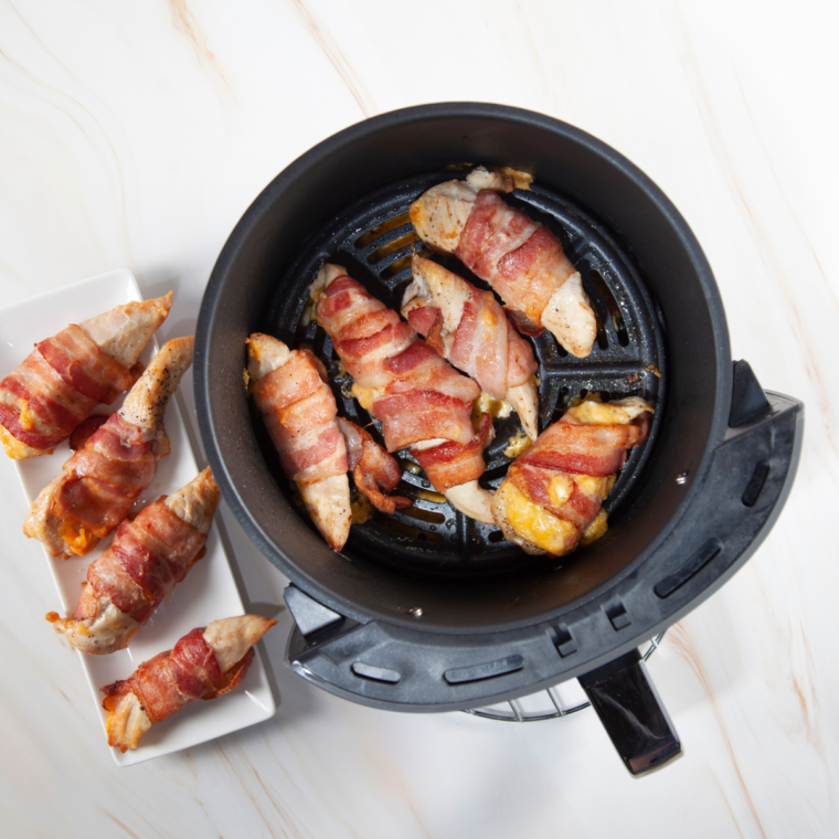 Serving plate of cheesy bacon wrapped chicken with toothpicks removed and herbs on top