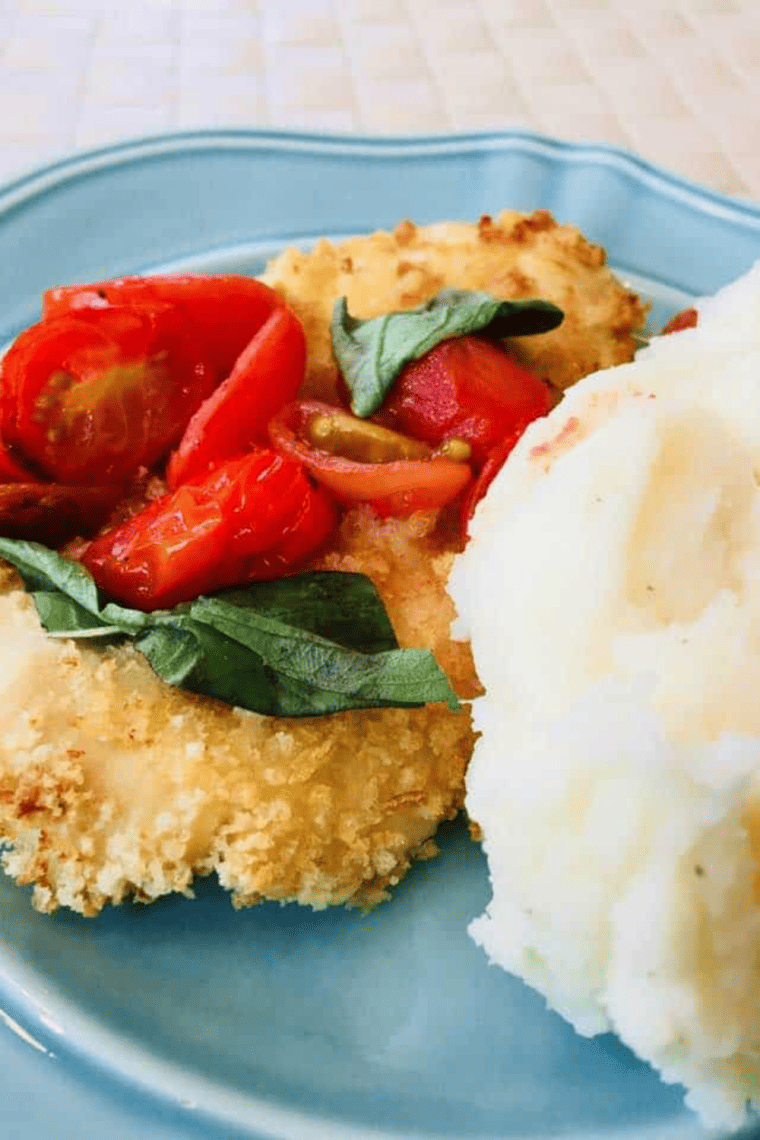 Crispy breaded chicken Milanese with tomato basil sauce, cut to show the juicy interior