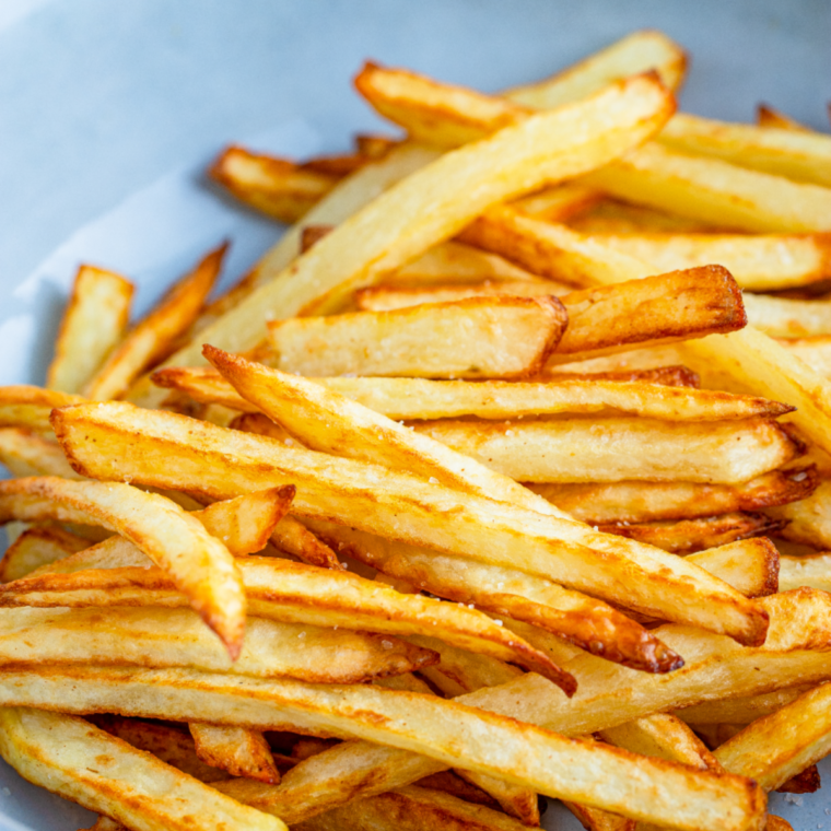 Golden brown, thin French fries piled high in a red carton, resembling copycat McDonald's fries made in an air fryer.
