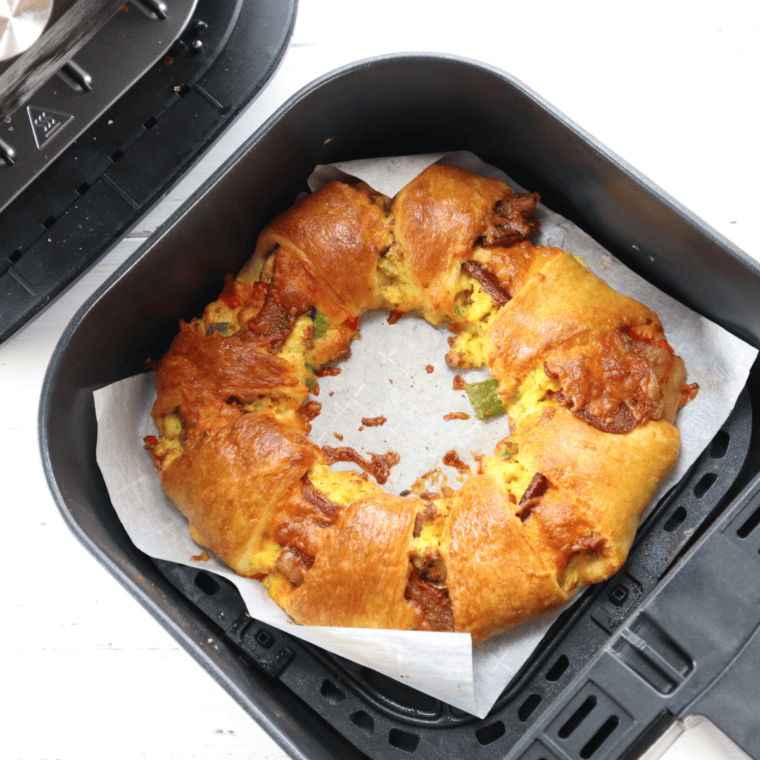 Golden crescent breakfast ring with eggs, bacon, peppers, and melted cheese in air fryer