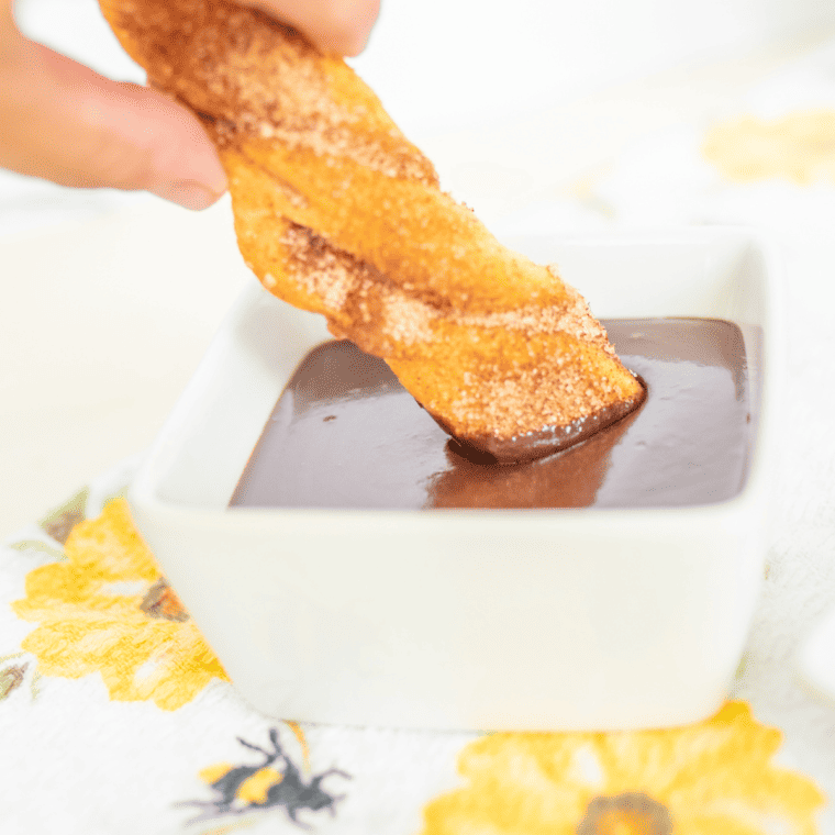 Golden crescent roll churros dusted in cinnamon sugar on parchment paper