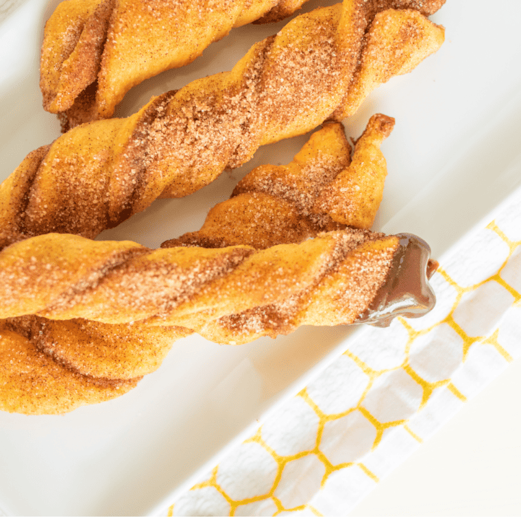 Stack of crispy crescent churros with melted chocolate for dipping