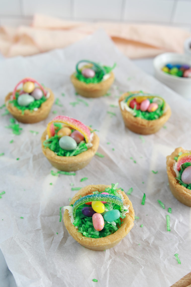 Air fryer Easter basket cookie cups filled with green coconut grass and colorful candies on a plate.