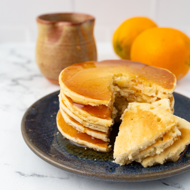 Stack of air fryer frozen pancakes topped with syrup and butter