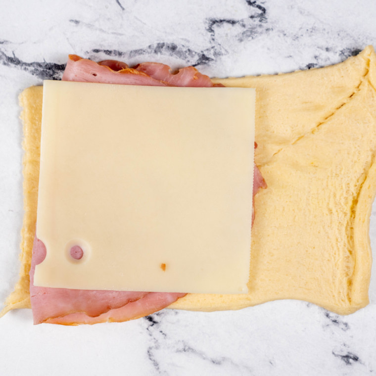 Image alt text: Fold the crescent roll dough over the fillings to shape the homemade ham and cheese hot pockets