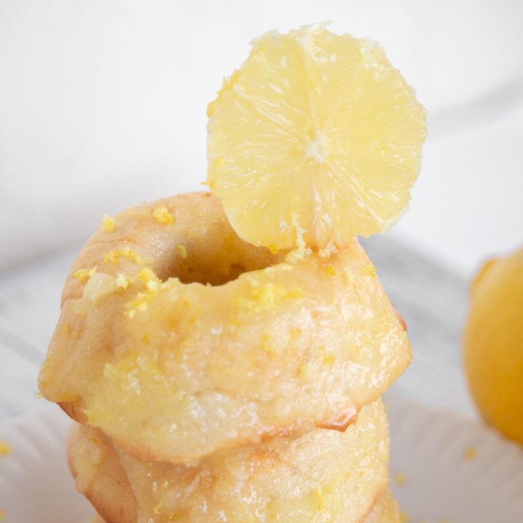 Air fryer lemon donuts with glossy lemon glaze, stacked and ready to serve on a white plate