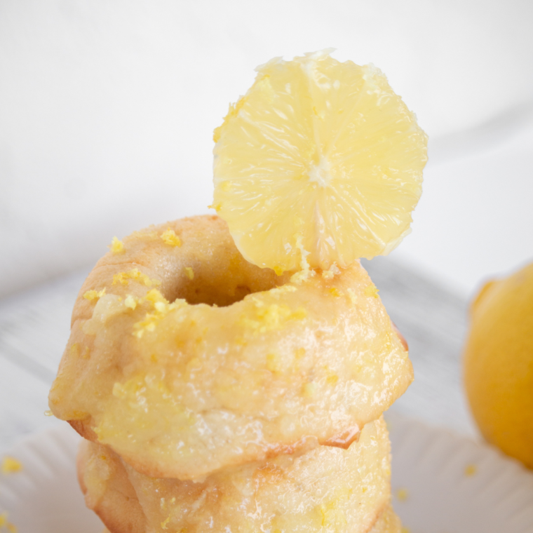 Freshly air-fried lemon donuts with glossy lemon glaze stacked on a plate ready to serve