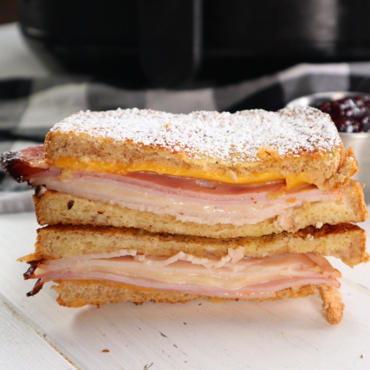 Air fryer Monte Cristo sandwich with ham, turkey, melted cheese, and powdered sugar
