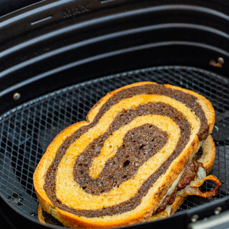 Cooking assembled Patty Melts in the air fryer at 370°F, toasting the bread and melting the cheese.