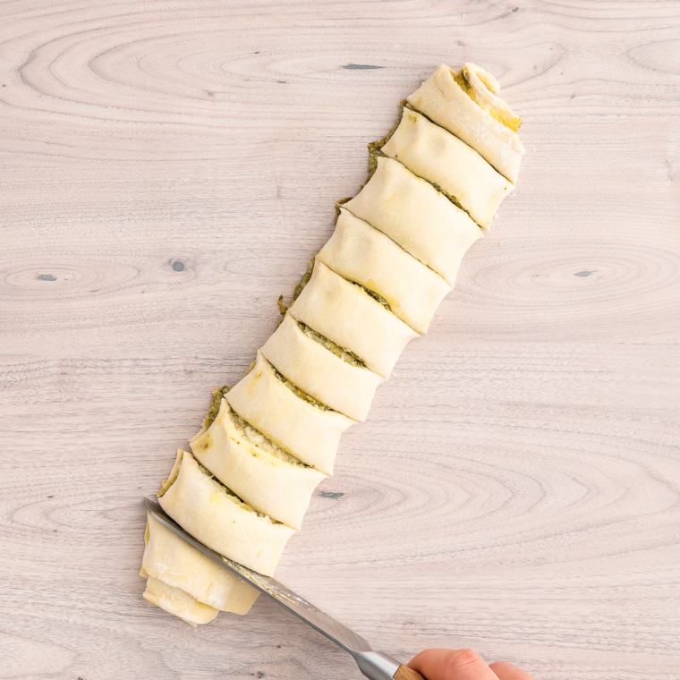 Slicing the rolled-up puff pastry into individual pinwheels.