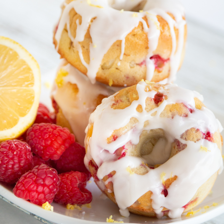 Air fryer raspberry lemon donuts with glaze on a plate