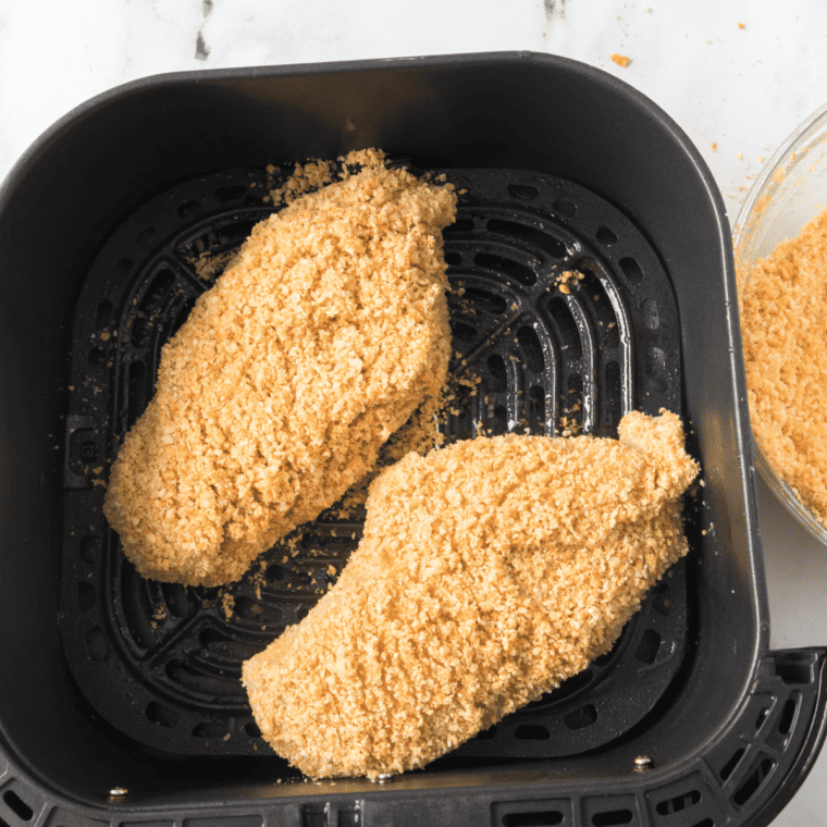 Place the coated chicken breasts in the air fryer basket, ready for cooking.