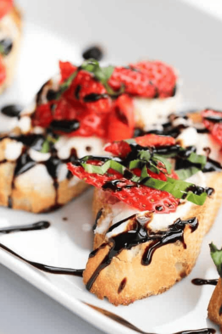 Overhead close-up of strawberry mascarpone bruschetta showing glossy balsamic glaze and basil