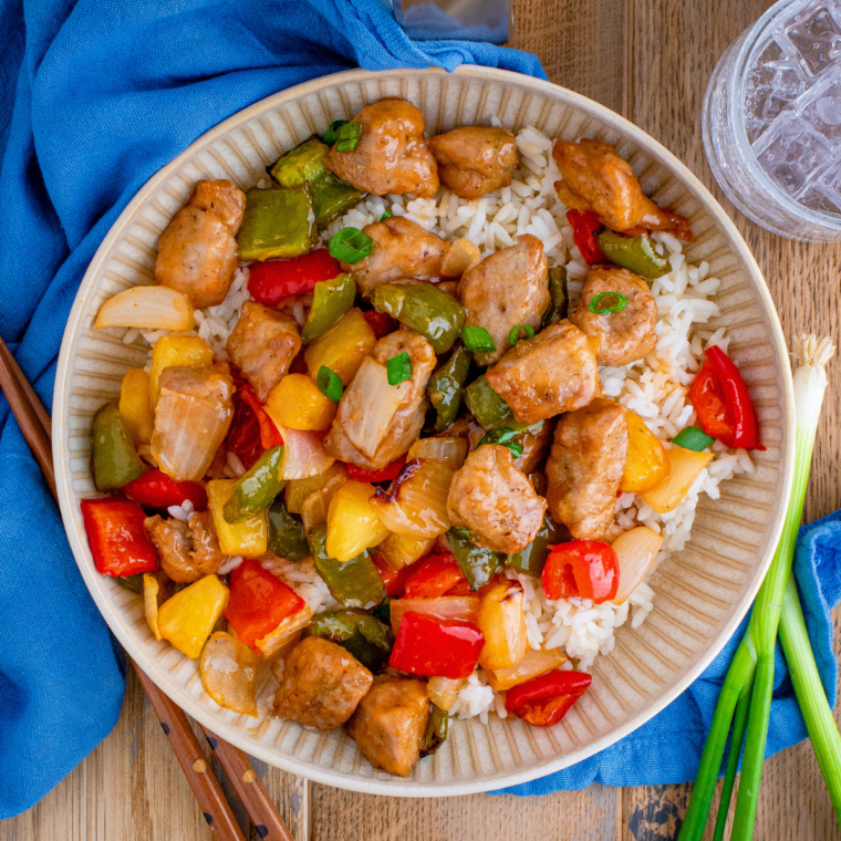 Crispy air fryer sweet and sour pork in a white bowl with chopsticks