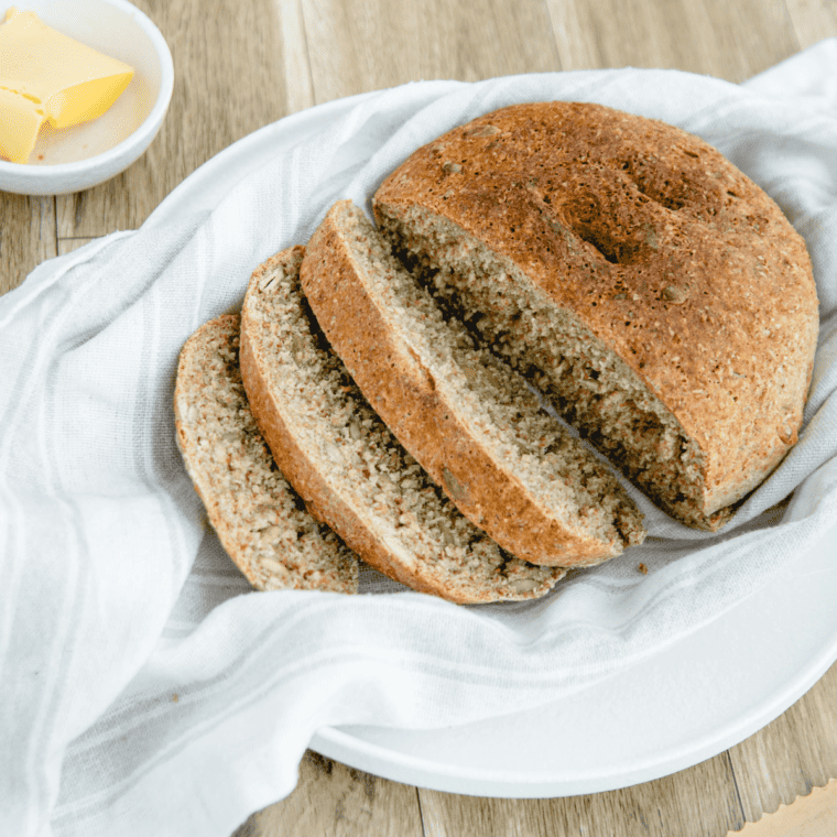 Golden-brown air fryer whole wheat bread loaf resting on a wooden cutting board