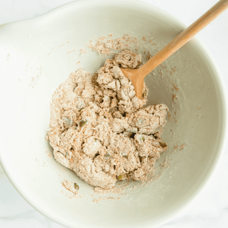 Whole wheat bread dough coming together in a glass mixing bowl