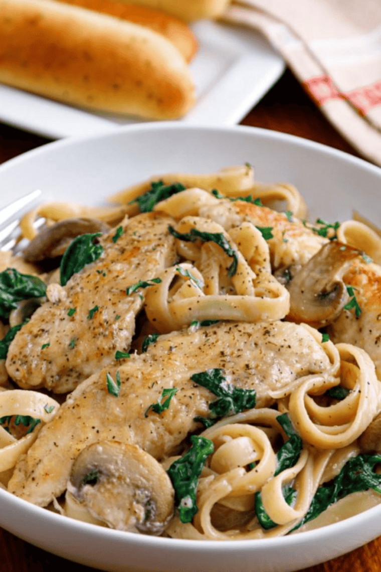 Plated Olive Garden Copycat Chicken Marsala Fettuccine garnished with fresh parsley and grated Parmesan cheese.