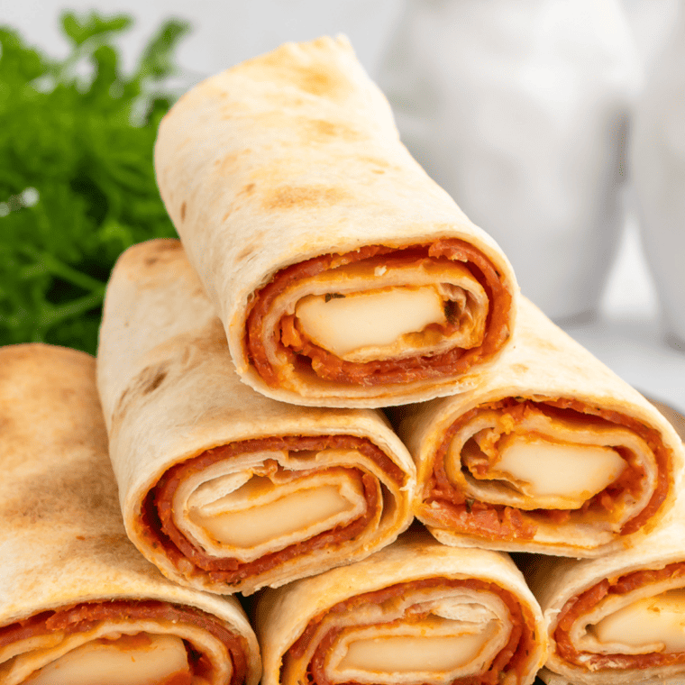 Image of serving suggestion with dipping sauce: "Air Fryer Pizza Roll Ups arranged on a platter with a small bowl of marinara sauce for dipping."
