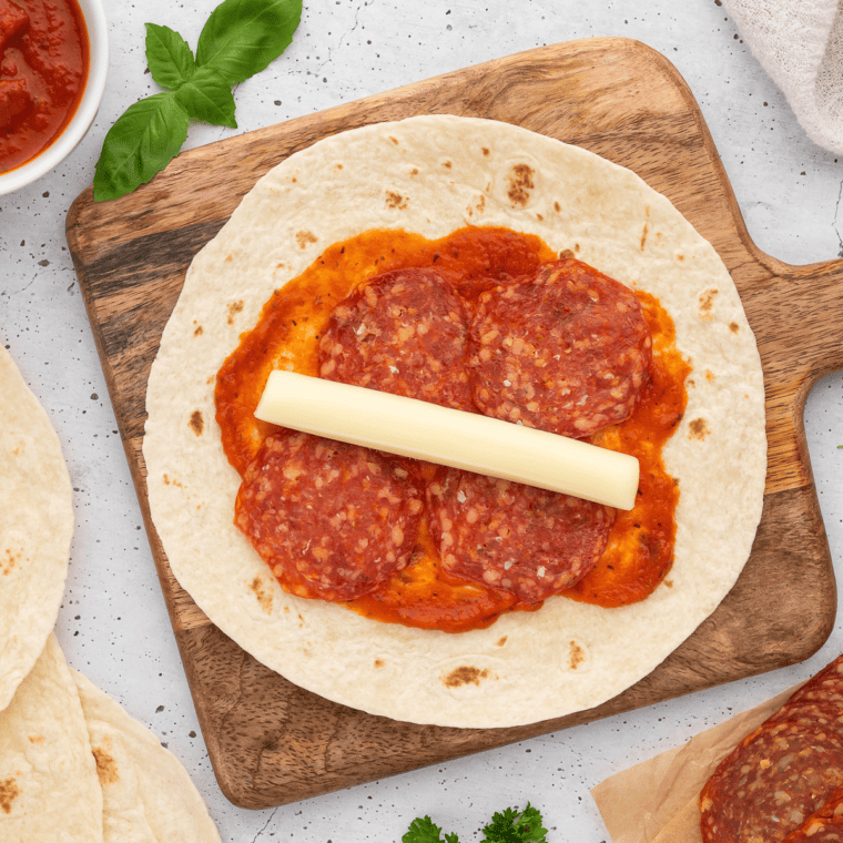 Add the diced mozzarella stick on top of the pizza sauce and pepperoni.