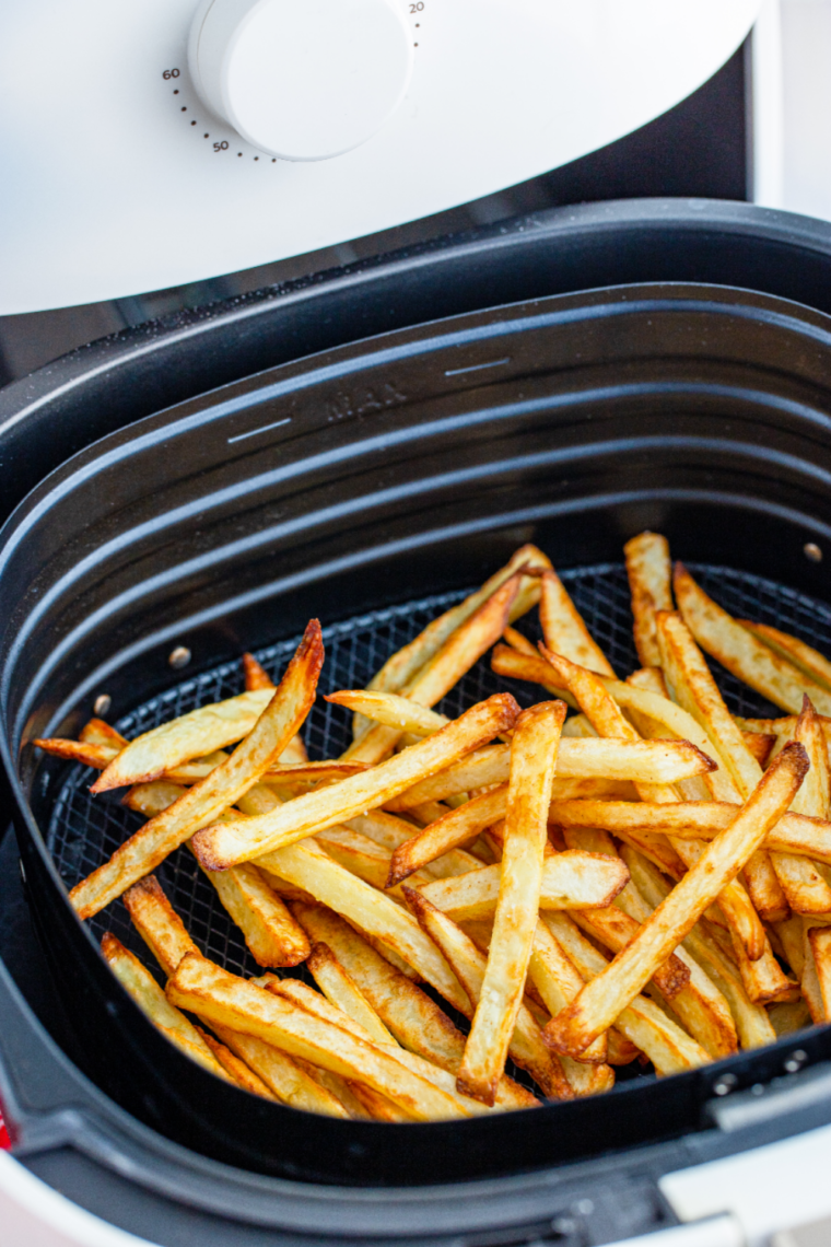 Golden brown, thin French fries piled high in a red carton, resembling copycat McDonald's fries made in an air fryer.
