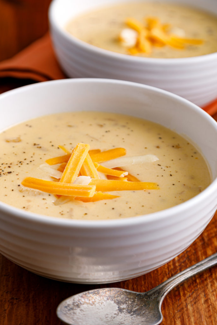 A creamy bowl of Outback Steakhouse Walkabout Onion Soup topped with melted cheese and served with a slice of toasted bread.
