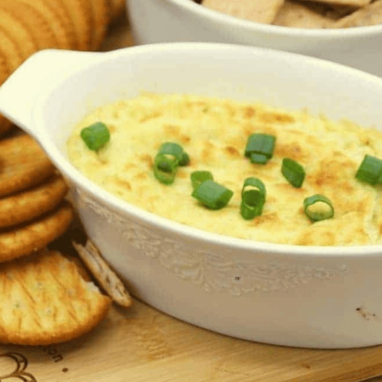 Golden-brown Air Fryer Hot Artichoke Dip garnished with parsley, ready to be served with dippers.