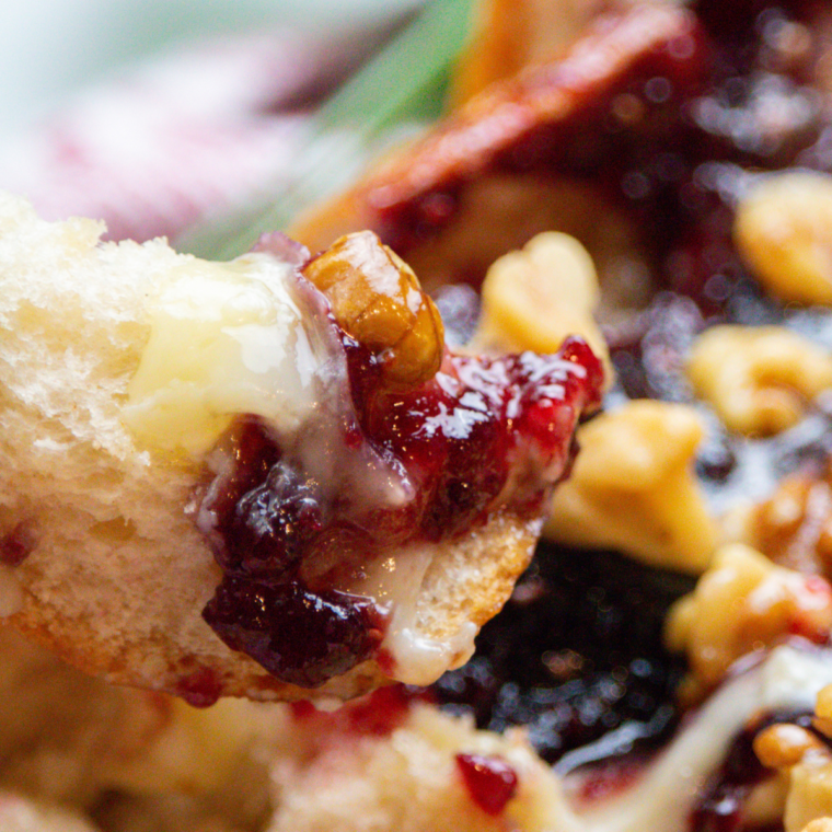 Close-up of golden pull-apart bread with gooey Brie and sweet raspberries"