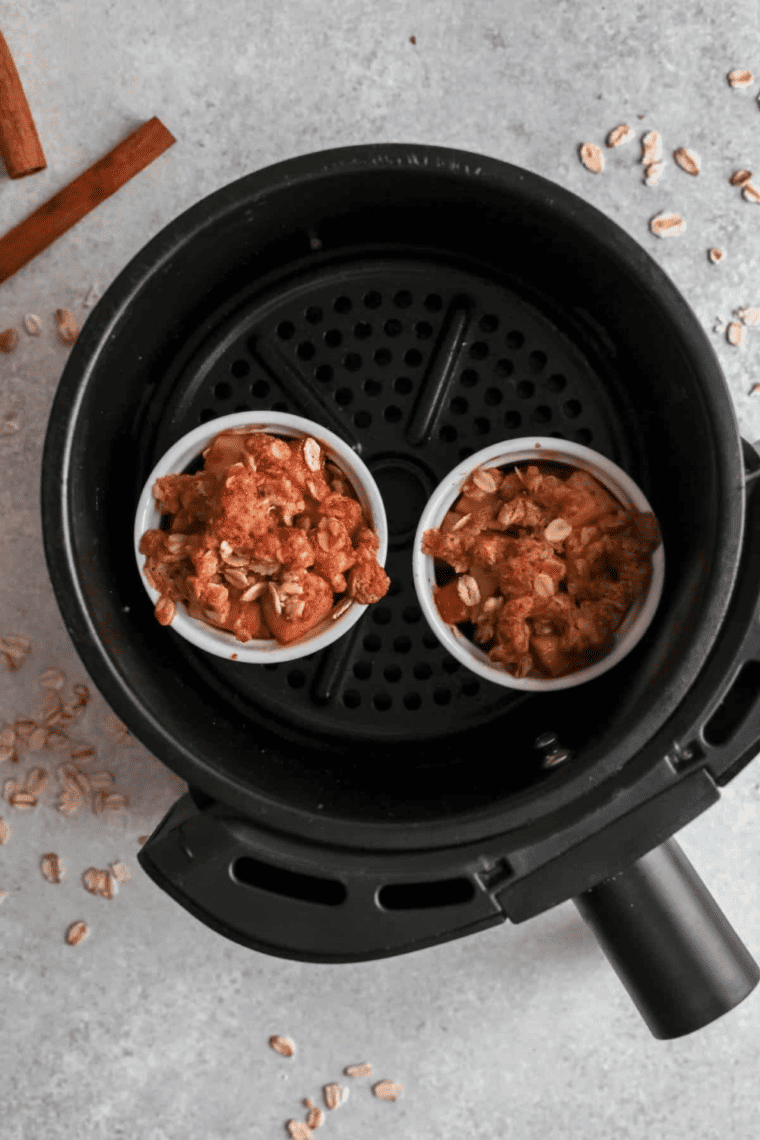 A close-up of the golden-brown apple crisp freshly cooked in the air fryer, with a spoon ready to serve.