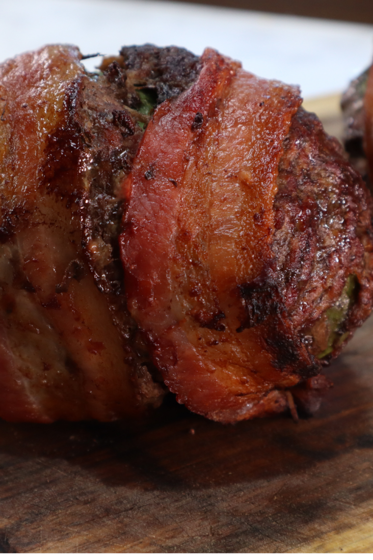 Sliced open air fryer bacon-wrapped avocado burger bomb showing melted cheese and creamy avocado center wrapped in beef and bacon