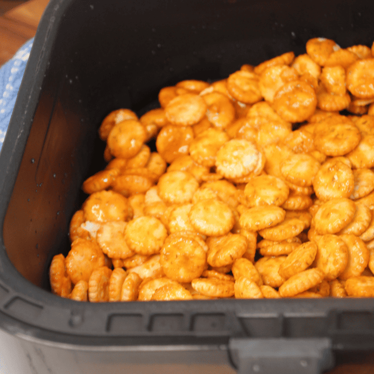 Spreading coated oyster crackers in a single layer in the air fryer basket.